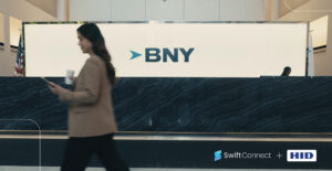 زنی که در دفتر BNY در حال قدم زدن است به همراه لوگوهای SwiftConnect و HID