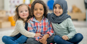 3 کودک نشسته و در حال لبخند زدن